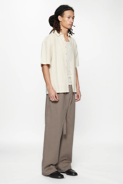 Side view of a person wearing the Hold SS Shirt in Off White and brown pants on a white background