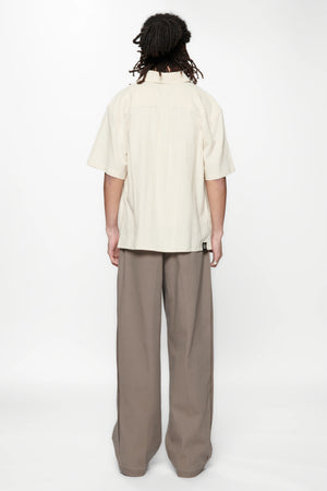 Behind view of a person wearing the Hold SS Shirt in Off White and brown pants
