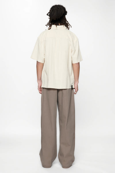 Behind view of a person wearing the Hold SS Shirt in Off White and brown pants