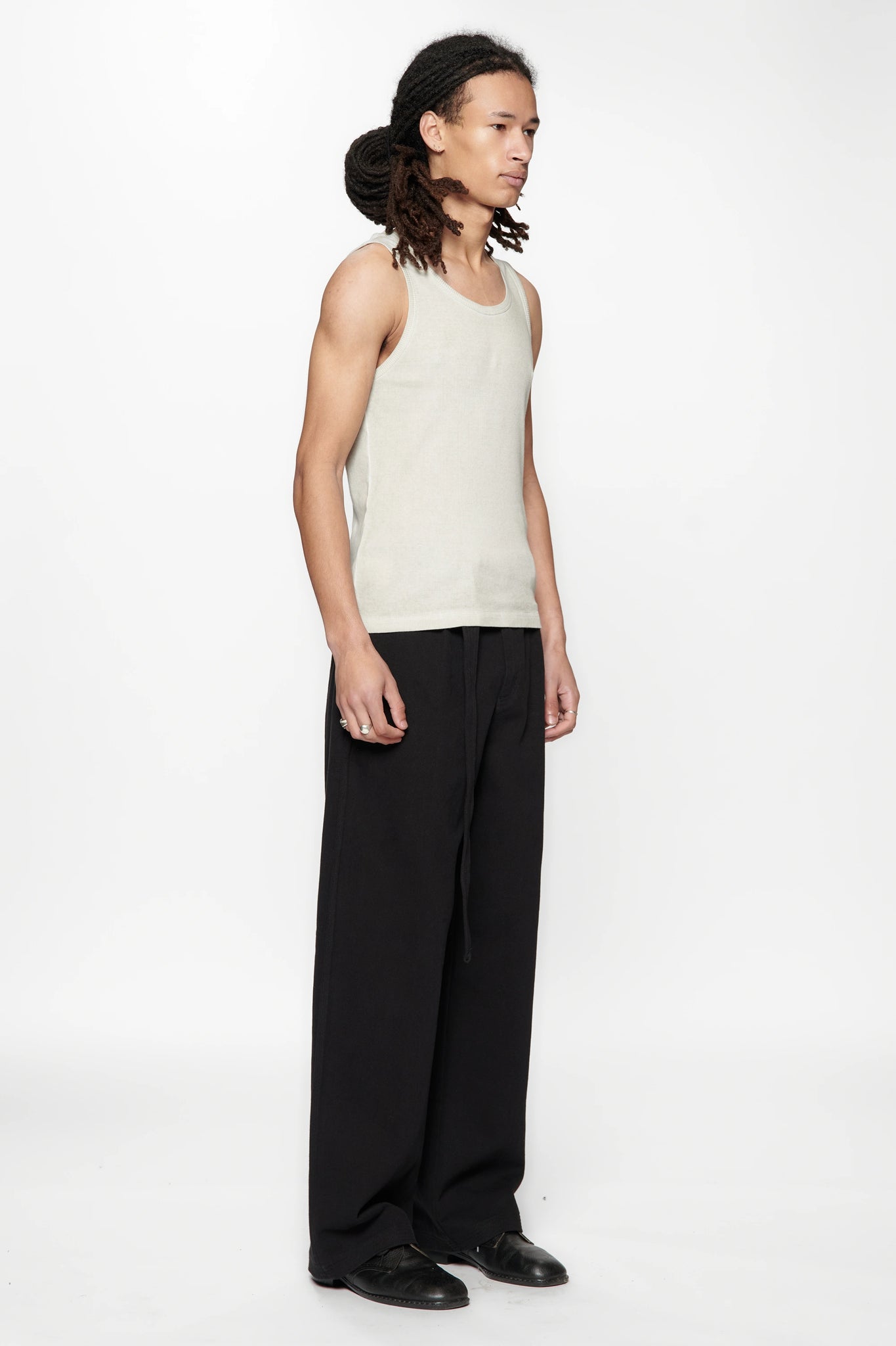 Side view of a person wearing a beige tank top and Pleated Work Pants in Black by Beach Brains