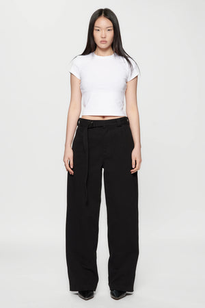 A woman wearing a white crop top and Pleated Work Pants in Black by Beach Brains