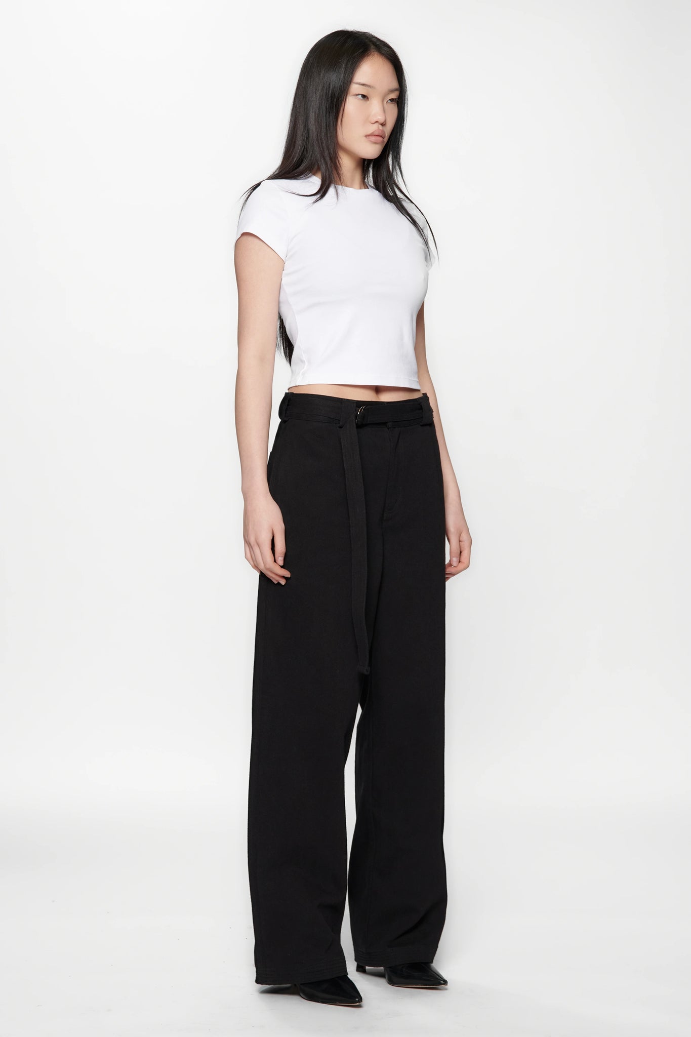 Side view of a woman wearing a white crop top and Pleated Work Pants in Black by Beach Brains