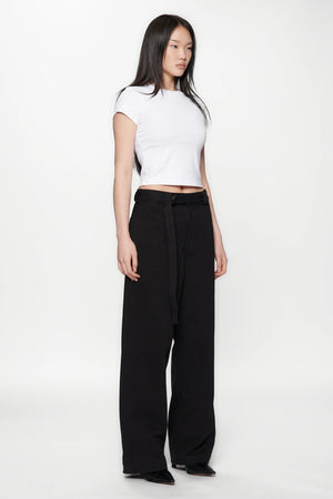 Side view of a woman wearing a white crop top and Pleated Work Pants in Black by Beach Brains