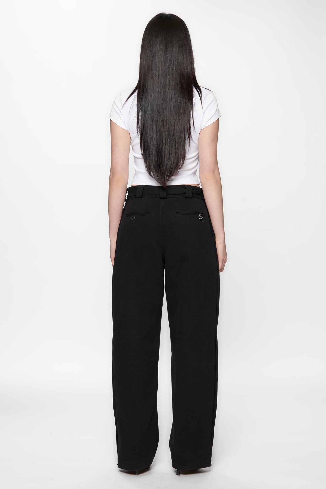 Behind view of a woman wearing a white crop top and Pleated Work Pants in Black by Beach Brains